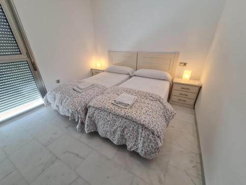 a white bedroom with a bed and two night stands at REf 107 DUPLEX DUNA PLAYA ZAHARA in Zahara de los Atunes