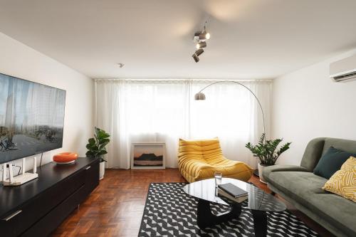 a living room with a couch and a tv at Flat and Fur 2BR Mid-Century 3mins to Nimman Airport in Chiang Mai
