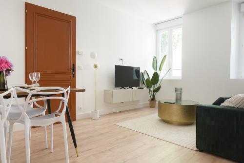 a living room with a table and a tv at Appartement de la Citadelle de Blaye - Spacieux & confort- 2 chambres in Blaye