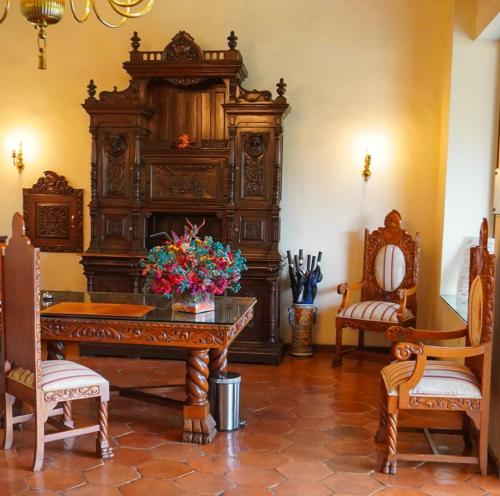 a large wooden cabinet in a room with two chairs at Hotel Hacienda Los Laureles in Oaxaca City