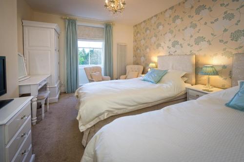 a bedroom with two beds and a desk and a television at Craig Y Glyn in Pwllheli