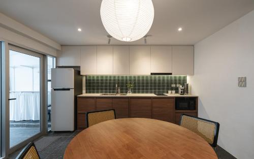 a kitchen with a wooden table with chairs and a refrigerator at Flat and Fur 2BR Mid-Century 3mins to Nimman Airport in Chiang Mai