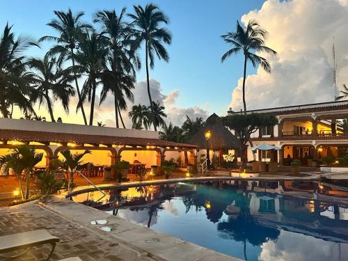 a large swimming pool in front of a building with palm trees at Hotel Posada Pablo de Tarso in San Patricio Melaque