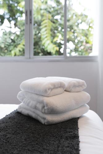 a stack of towels sitting on top of a rug in front of a window at Flat and Fur 2BR Mid-Century 3mins to Nimman Airport in Chiang Mai