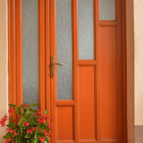 an orange door with a plant in front of it at Neuhercz Apartmanok Halászi in Halászi