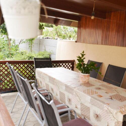 a table with chairs and a plant on a patio at Neuhercz Apartmanok Halászi in Halászi