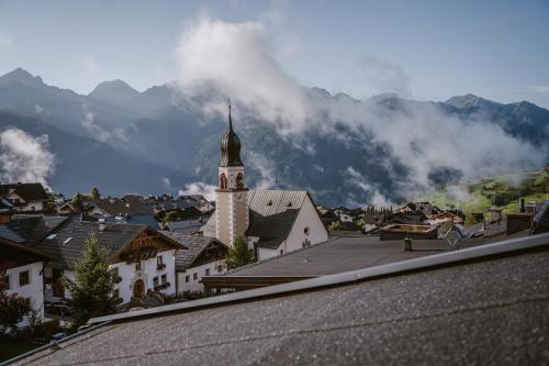 a small town with a clock tower in front of a mountain at ... mein romantisches Hotel Toalstock in Fiss