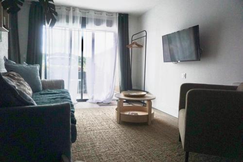 un salon avec un canapé, une table et une télévision dans l'établissement Suite GOLD proche Disney et aéroport Roissy Charles de Gaulle, à Villevaudé