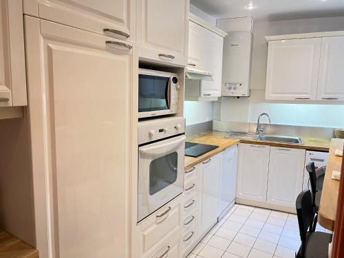 une cuisine blanche avec des armoires blanches et un micro-ondes dans l'établissement Colisee, à Paris