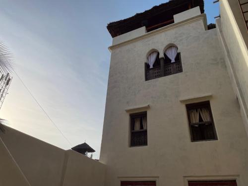 a tall white building with two windows on it at Umma House in Lamu