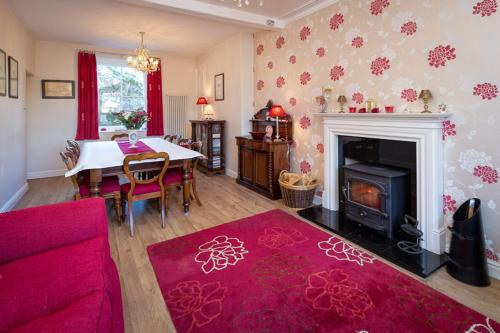 a living room with a red couch and a fireplace at Craig Y Glyn in Pwllheli