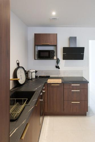 une cuisine avec des placards en bois et une horloge sur le comptoir dans l'établissement Appartement de l'UNESCO de Blaye - Proche centre ville & citadelle - Lumineux et Spacieux, à Blaye