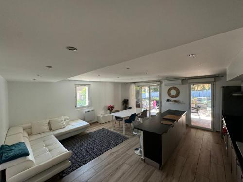 un salon avec un canapé blanc et une table dans l'établissement Morgiou Sormiou Marseille T4 climatisé familial - 3 Chambres - Terrasse bois - jardin privatif - Calanques à pied - Plages & Vélodrome à 10 min - Idéal Familles & Randonneurs & Grimpeurs - Escalade à 5 min - Marseille Sud, à Marseille