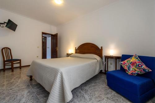 a bedroom with a bed and a blue chair at Afonso's House Gerês I in Braga