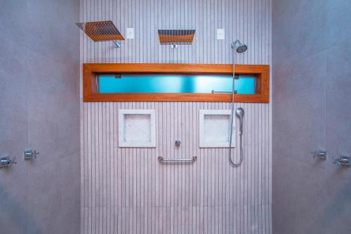 a bathroom with a shower with a mirror and a window at Pousada Cavaleiro dos Pireneus in Pirenópolis