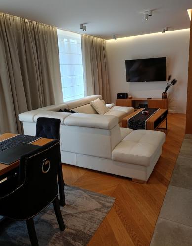 un salon avec un canapé blanc et une télévision dans l'établissement Apartament Glamour z wyjątkowym widokiem i klimatyzacją, à Ustroń