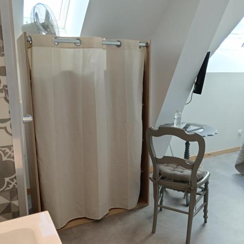 a shower curtain and a chair in a room at L'ancienne forge 3 chambres d'hôtes à l'étage la forge , l'enclume et le marteau in Louvetot