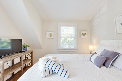 a white bedroom with a large bed and a flat screen tv at Oyster Beach Bungalow in Chatham