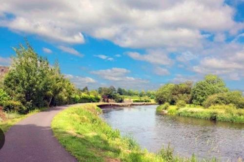 a path next to a river with trees and clouds at O'Neill's Self Catering Cottage- close to Cashel in Tipperary