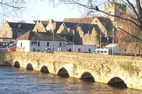 a bridge over a river with buildings in the background at O'Neill's Self Catering Cottage- close to Cashel in Tipperary