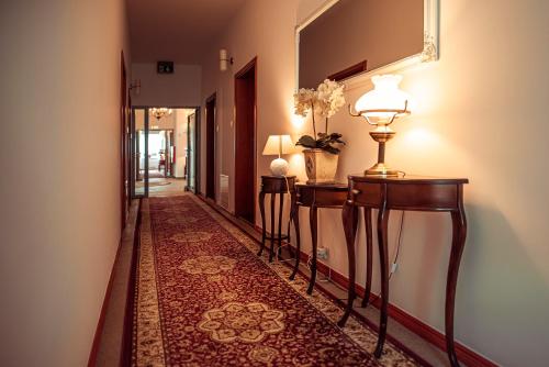 a hallway with two tables and a mirror at Hotel Maxim Kwidzyn in Kwidzyn
