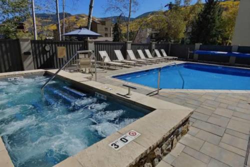 a swimming pool with chairs and an umbrella at Best location in the heart of lions head, Ski lockers, jacuzzi and pool in Vail