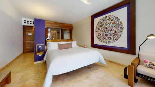 a bedroom with a white bed and a large painting on the wall at Hotel Xcaret Arte - All Parks All Fun Inclusive - Adults Only in Playa del Carmen