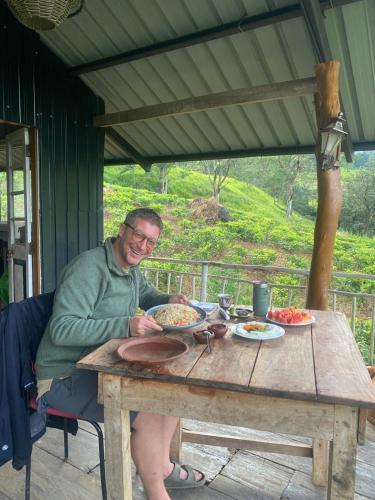 a man sitting at a table with plates of food at Dunali Mountains - Galaha in Galaha Town