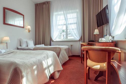 a hotel room with two beds and a desk at Hotel Maxim Kwidzyn in Kwidzyn