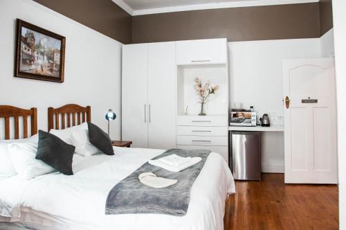 a bedroom with a white bed with a wooden floor at 6 on Kloof Guest House in Bredasdorp
