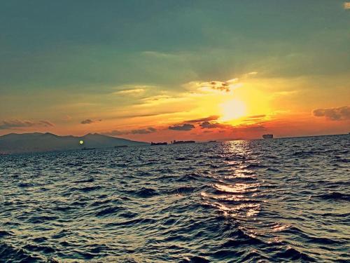 a sunset over the ocean with the sun setting at Maris Alsancak City Center in Konak