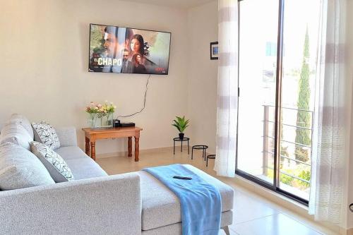 a living room with a couch and a tv on the wall at Departamento Tequis, totalmente nuevo en el corazón de SLP in San Luis Potosí