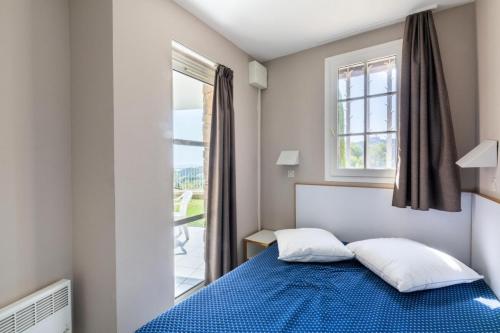 une chambre avec un lit bleu et une fenêtre dans l'établissement Résidence le Hameau de Cap Esterel - maeva Home - Appartement 2 Pièces 5 Personnes - Confort MAE-1130, à Saint-Raphaël