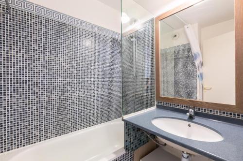une salle de bain avec un lavabo, une baignoire et un miroir dans l'établissement Résidence le Hameau de Cap Esterel - maeva Home - Appartement 2 Pièces 5 Personnes - Confort MAE-1130, à Saint-Raphaël