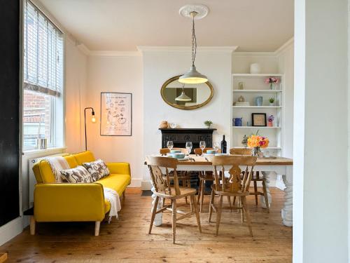 a dining room with a yellow couch and a table at NEW Spacious Family Home with Parking & Garden - Sleeps 6 - Perfect for Families in Canterbury