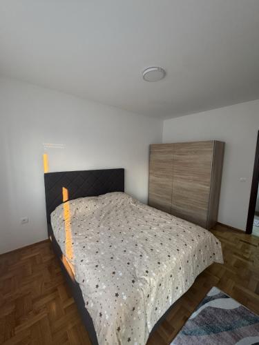 a bedroom with a bed and a wooden cabinet at Apartman Podgorica in Podgorica