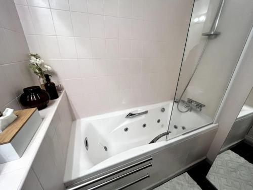 La salle de bains blanche est pourvue d'une douche et d'une baignoire. dans l'établissement Logement 85m2, hypercentre, balcon, parking, clim, à Clermont-Ferrand