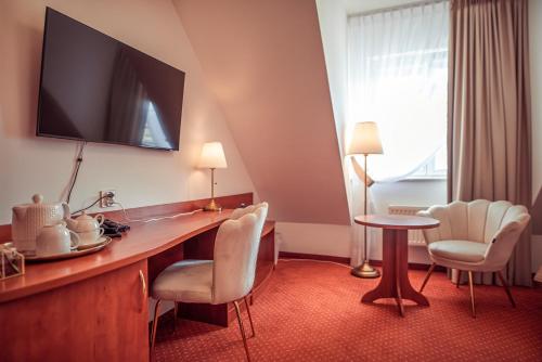 a hotel room with a desk with chairs and a tv at Hotel Maxim Kwidzyn in Kwidzyn