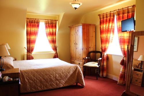 a bedroom with a bed and a chair and windows at Keanes of Curraheen in Tralee