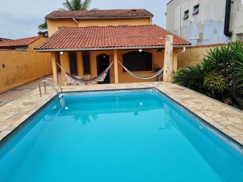 a swimming pool in front of a house at Casa com piscina in Bertioga