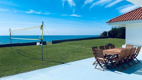 Una mesa y sillas con una red de voleibol. en Best Beach Front Villa with Heated Pool - Sea La Vie, en Fão