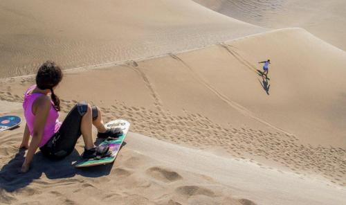 a woman sitting on a skateboard in the sand at Luxury Beach Villa with Private Pool, Jacuzzi, Beach Club Access with Restaurant & Adventure Nearby in Baní