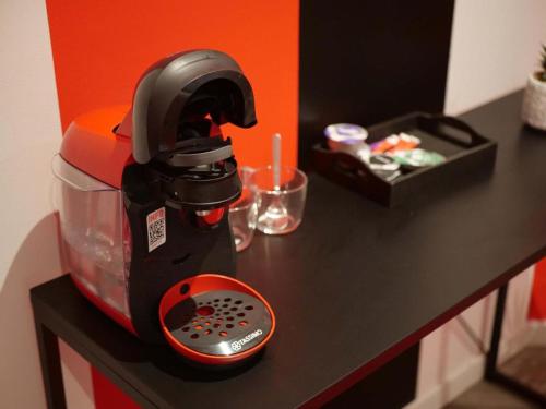 un mélangeur noir et orange assis sur un comptoir dans l'établissement Suite ROMANTICA Balnéo - Olympe Suites & Spa Lille, Croix, Roubaix, à Croix