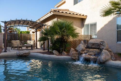 a swimming pool with a waterfall in front of a house at Gilbert Douglas in Gilbert