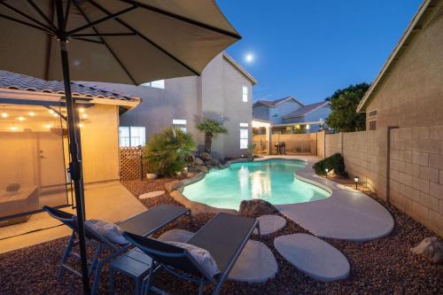 a swimming pool with two chairs and an umbrella at Gilbert Douglas in Gilbert