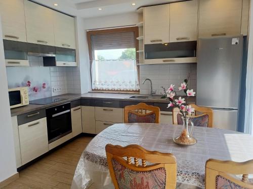 a kitchen with a table with a vase of flowers on it at Biała Grusza in Pieszyce