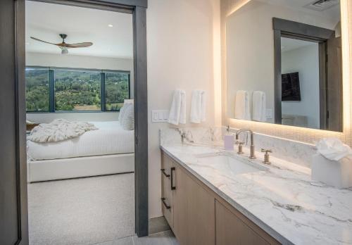 Un baño con lavabo, espejo y cama. en ONE Riverfront #402 - Avon, en Avon