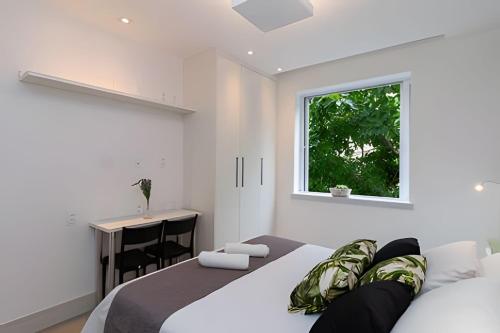 a bedroom with a bed and a desk and a window at Apto Copacabana 200 da Praia - Suíte + Lava&Seca in Rio de Janeiro