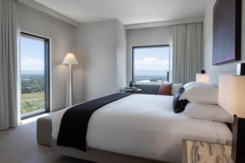 a bedroom with a large white bed with large windows at Kimpton Claret Hotel by IHG in Denver