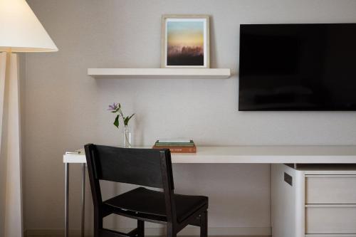 a black chair sitting next to a desk with a television at Kimpton Claret Hotel by IHG in Denver